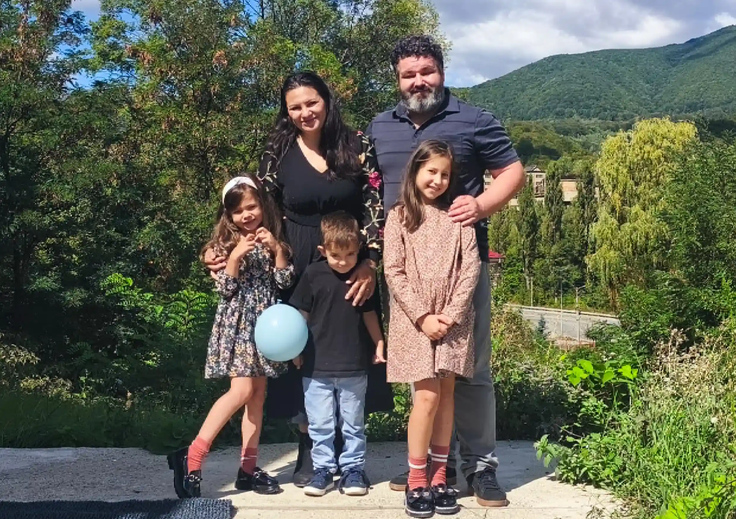 Familia care a inițiat proiectul, fotografiată în aer liber la Lupeni, cu dealurile împădurite ale Văii Jiului în fundal.